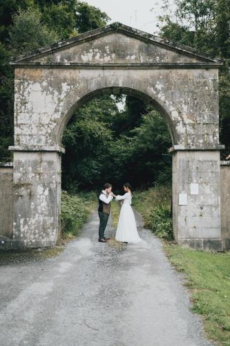 a bride and groom standing under an archway at Cloverhill Gate Lodge in Cloverhill
