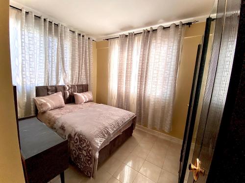 1 dormitorio con cama con almohadas y cortinas rosas en Lovely 3-Bed Apartment in Mogadishu en Mogadiscio