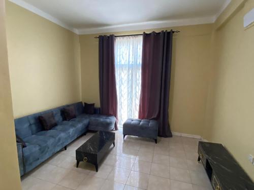 sala de estar con sofá azul y ventana en Lovely 3-Bed Apartment in Mogadishu en Mogadiscio