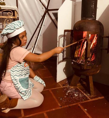 a little girl sitting on the floor next to an oven at Reserva Natural Bosque del Colibri in Guatavita