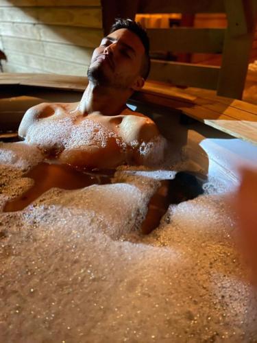 a man laying in a bath tub with his head in the water at Entre Verdes Hotel & Glamping in Medellín