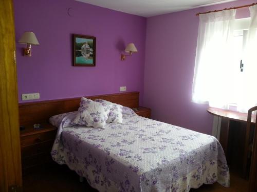 a bedroom with a bed with purple walls and a window at Pensión Toranda in Niembro