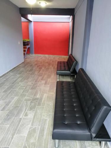 a waiting room with a couch and a red wall at Habitaciones del Pacifico in Zihuatanejo