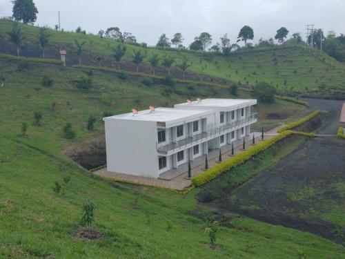 a white building on a hill with a field at Hotel Takuara in Vergara