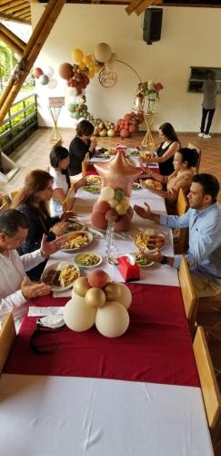 a group of people sitting around a table with food at Hotel Takuara in Vergara