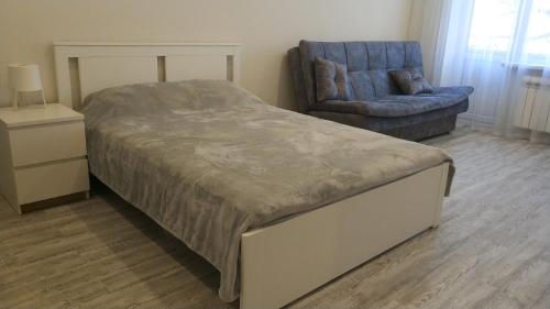 een slaapkamer met een bed en een blauwe stoel bij Апартаменты на первой линии до моря 50 метров in Novorossiejsk