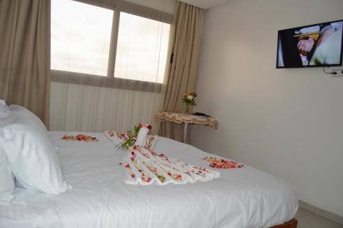 a bedroom with a white bed with flowers on it at Hôtel Zahrat Souss -Inezgane in Inezgane