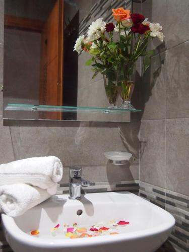 a bathroom sink with a vase of flowers on it at Hôtel Zahrat Souss -Inezgane in Inezgane