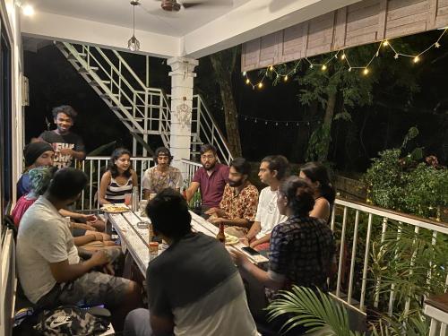 a group of people sitting around a table on a patio at ROOTSVILLA VAGATOR - Longstays, Coworking Backpacker's Hostel in Vagator