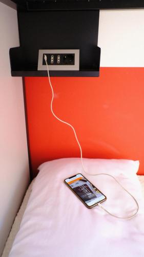 a cell phone on a bed with a clock on it at Hotello Hostel in Trieste