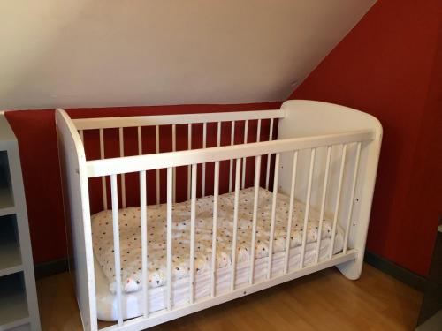 a white crib in a room with a red wall at Holiday home Gite Saint Donat in Rendeux