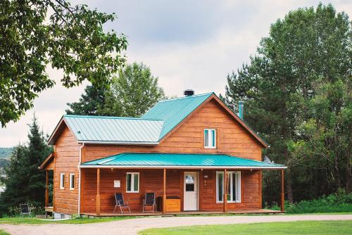 a wooden house with a blue tin roof at Ermitage Saint-Antoine in Lac-Bouchette