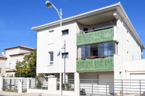 un edificio blanco con un balcón verde en La Roseliere, en Le Grau-du-Roi