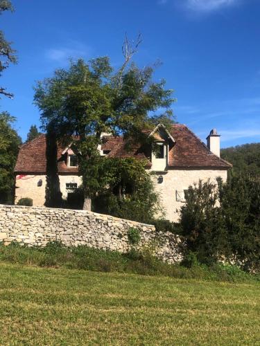 une maison avec un arbre derrière un mur en pierre dans l'établissement Le Mas de Laval, à Saint-Cirq-Lapopie