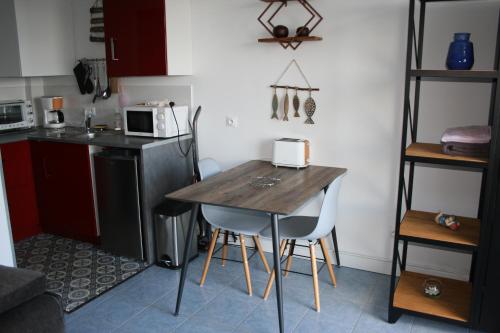 escapade en mer في أولت: مطبخ صغير مع طاولة وكراسي خشبية
