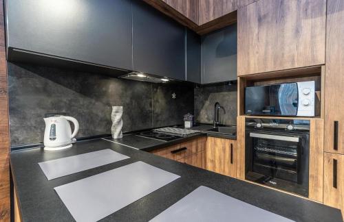 a kitchen with a black counter top and wooden cabinets at luxury apartments Smartplaza Obolon metro Minskai in Kyiv