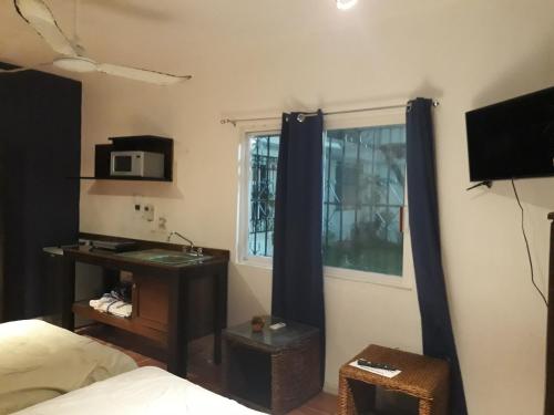 a bedroom with a bed and a window with a microwave at Bea rooms and studios in Cozumel