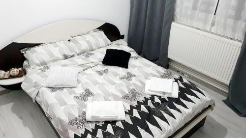 a bed with black and white sheets and pillows at Apartament Ella ,wifi inclus la Straja ,Lupeni ! in Lupeni