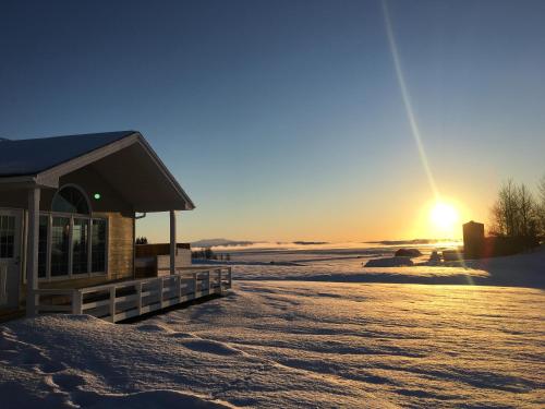 a building in the snow with the sunset in the background at Iceland Inn Lodge, entire place with hot tub. in Selfoss