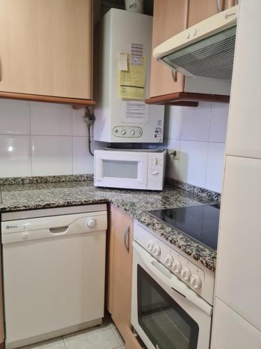 a kitchen with a stove and a microwave at Tuhogarencerler parking y taquilla en pistas in Cerler