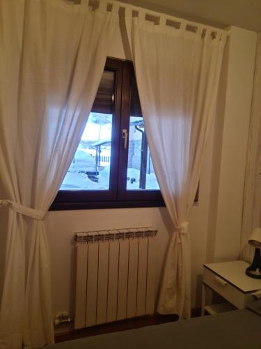a window with white curtains next to a radiator at Tuhogarencerler parking y taquilla en pistas in Cerler