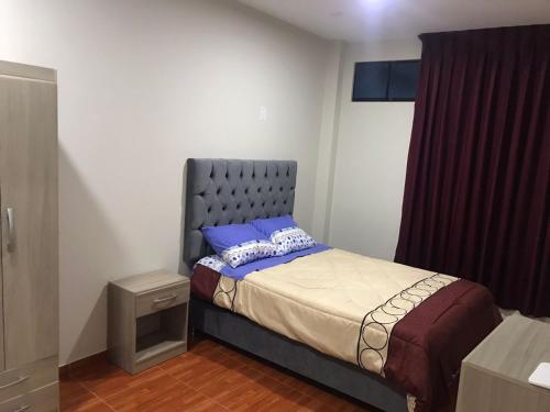 a small bedroom with a bed with a blue headboard at 100- departamento céntrico en chorrillos in Lima