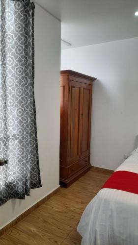 a bedroom with a bed and a wooden cabinet at Casablanca 2 in Tacna