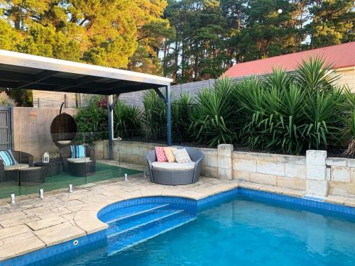 a swimming pool with a couch and a chair next to a swimming pool at Bella Cosa in McLaren Vale