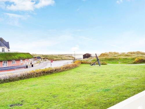 a grassy field next to a road with a house and a sign at 4 person holiday home in Fan in Fanø