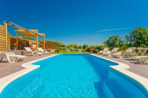 basen z białymi krzesłami i błękitnym basenem w obiekcie Apartments Marinko-with pool w mieście Barban