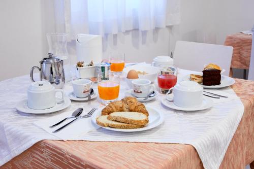 a table with a breakfast of bread and orange juice at Le Vette Room&Breakfast in Rovereto