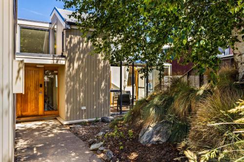 a house with a wooden door and a sidewalk at Sun-filled on Wakatipu in Queenstown