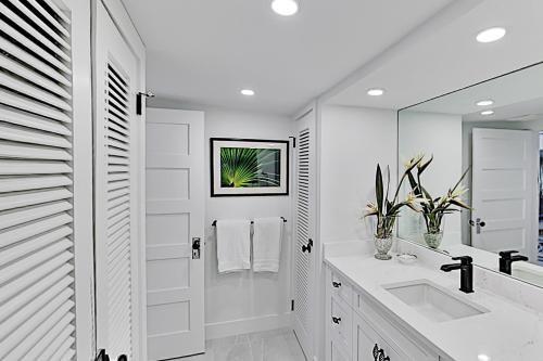 a white bathroom with a sink and a mirror at Anything Is Possible in Sarasota
