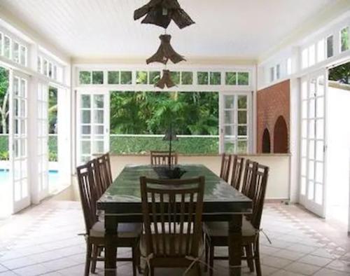 a dining room with a green table and chairs at Casa em Condomínio, PÉ NA AREIA, praia Guaratuba in Bertioga