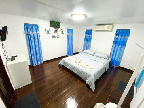 a bedroom with blue curtains and a bed with a wooden floor at Jamsai Resort in Phu Khieo