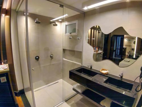 a bathroom with a shower with a sink and a mirror at Motel Dallas in Belo Horizonte