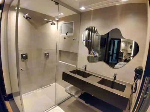 a bathroom with a shower with a sink and a mirror at Motel Dallas in Belo Horizonte