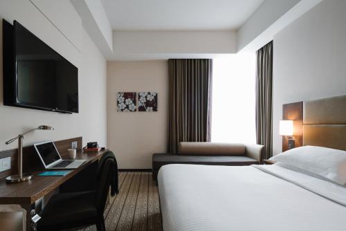 a hotel room with a bed and a desk with a laptop at Hotel Traveltine in Singapore