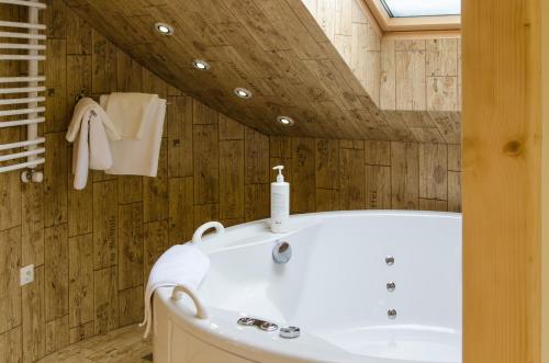 a bathroom with a white tub and a wooden ceiling at Hata Hutsula in Mykulychyn