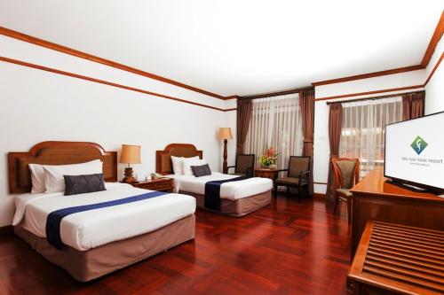 a hotel room with two beds and a flat screen tv at Felix River Kwai Resort - SHA Plus,Certified in Kanchanaburi