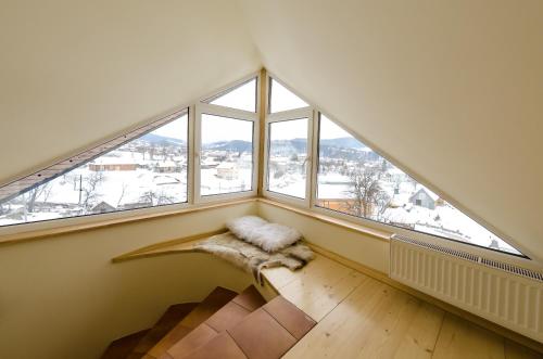 an attic room with large windows and a rug at Hata Hutsula in Mykulychyn
