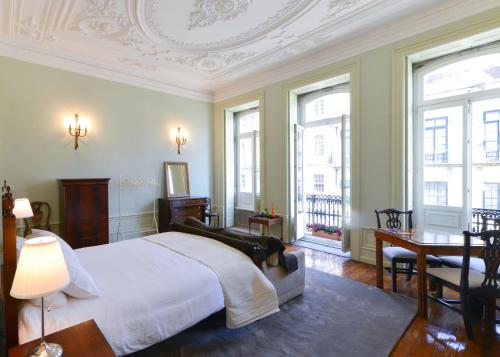 a bedroom with a bed and a desk and windows at Maison des Amis Porto in Porto