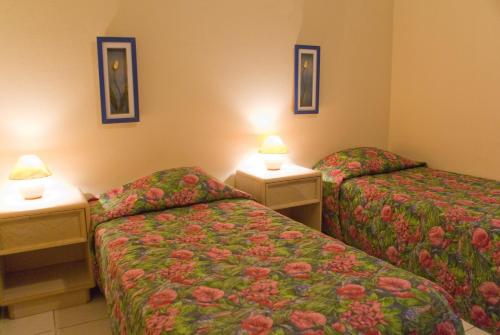 a hotel room with two beds and two lamps at Camacuri Apartments in Oranjestad