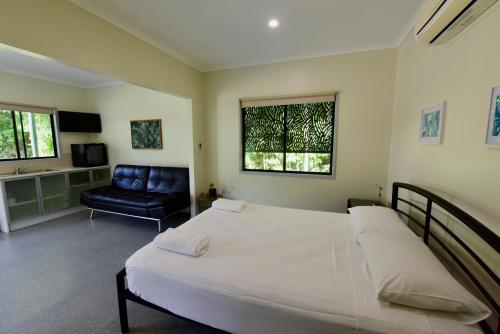 een slaapkamer met een groot wit bed en een stoel bij Daintree Peaks ECO Stays in Daintree