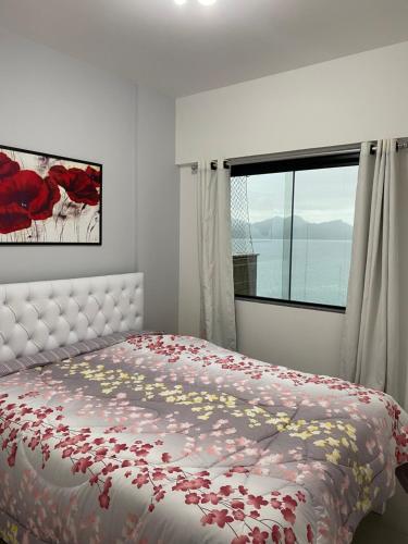 um quarto com uma cama com flores vermelhas em APARTAMENTO PORTO REAL RESORT VISTA ESPETACULAR em Mangaratiba
