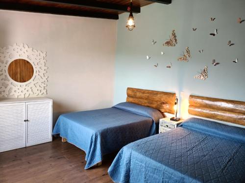 two beds in a room with butterflies on the wall at Cabaña La Lomita in Mazamitla