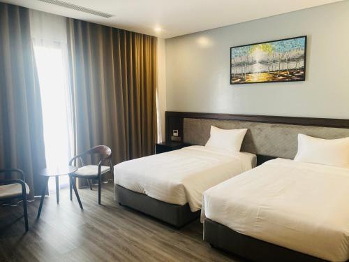 a hotel room with two beds and a table at DIAMOND HOTEL VÂN ĐỒN in Cẩm Phả