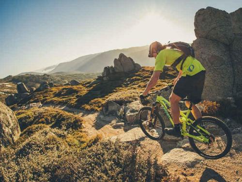 a man riding a bike on a rocky hill at Khione 1 - 3BR Modern Townhouse l Mountain Views l WiFi l BBQ l Smart TV in Jindabyne