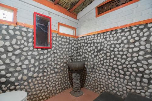a bathroom with a toilet and a wall covered in logs at RedDoorz near Farmhouse Lembang in Bandung