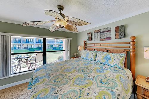 a bedroom with a bed with a ceiling fan and a window at Sea Fair Condo Unit 12128 in St. Augustine